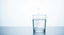 A clear glass of hydrogen-rich water with fine bubbles rising, set on a clean light surface with abundant white space