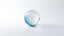 A clear glass sphere holding a few small bubbles, resting on a pale white surface in soft light